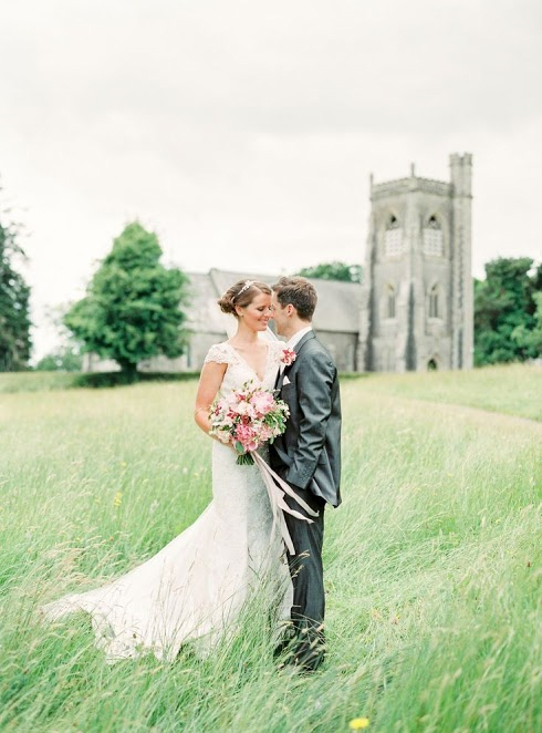 Photo by: Peaches & Mint - Look as the wind brings movement to this photo, delicately playing with the ribbon of the bride’s bouquet and surrounds this young couple with a bed of bowing foliage. With a castle in the background and greenery all around, picturing yourself here comes naturally.