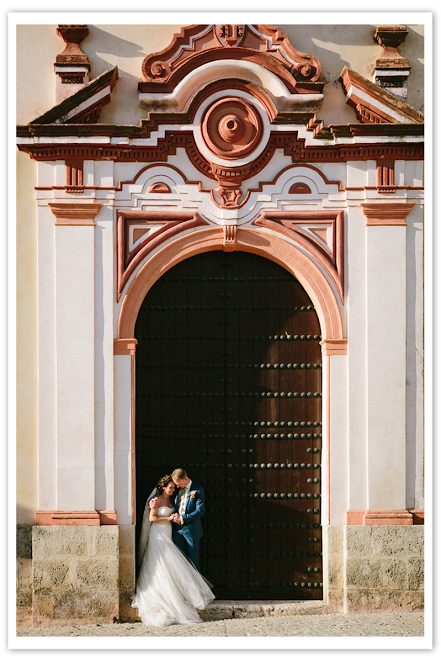 Photo by: Joel Bedford - A lively moment caught on film; this Spanish archway is the perfect place for a bold personality and a long lasting memory. With the heavy architecture contrasting with the bride’s delicately layered dress and the old-fashioned blue tux, this moment is a picture worth mounting on your mantel.